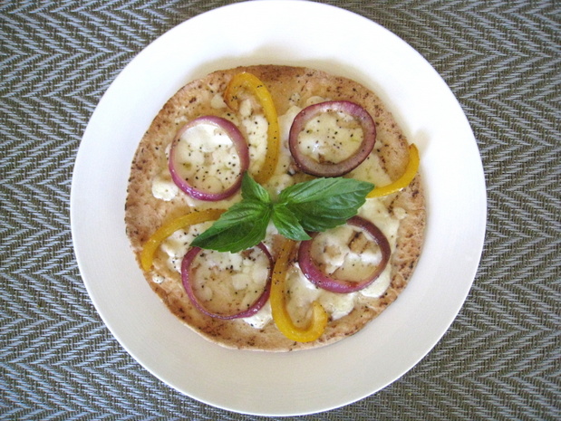 A Pita pizza with onion, bell pepper and basil